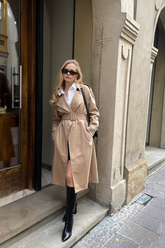 a lady wears a camel double-breasted trench coat with black boots